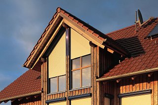 Außenansicht eines modernen Holzhauses, ausgestattet mit Schrägrollläden von Roma