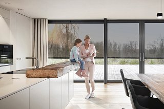 Mutter und Tochter stehen in Küche und steuern integrierte Smart-Home-Technik mit Hilfe eines Tablets