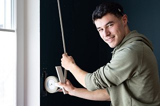 Junger Mitarbeiter montiert Rollladen