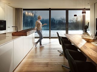 Frau steht abends in Küche und hält Fernbedienung in den Händen