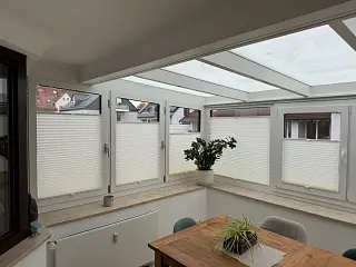 Weiße Plissees an Fenstern im Wohnbereich, umgesetzt von der Schuhbauer junior GmbH